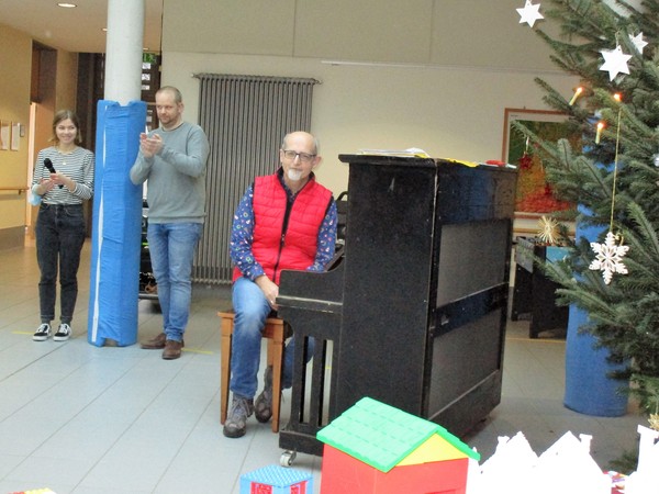 Das Bild zeigt Herrn Hesker und Frau Brüggemann bei der Begrüßung und Herrn Kramer am Klavier.