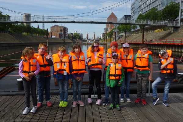 Ein Foto zeigt die Klasse E2a in Schwimmwesten bei ihrem Ausflug zum Duisburger Hafen.