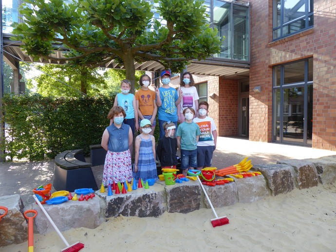 Das Foto zeigt die Klasse 4a mit dem neuen Sandspielzeug am Sandkasten der Brückenschule.