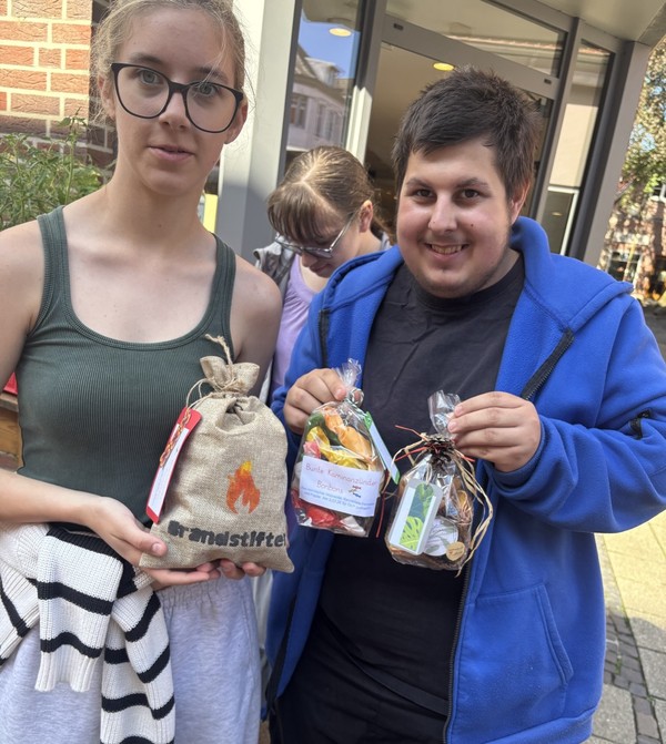 Das Foto zeigt zwei Schüler:innen  der Kreativgruppe mit ihren Produkten.