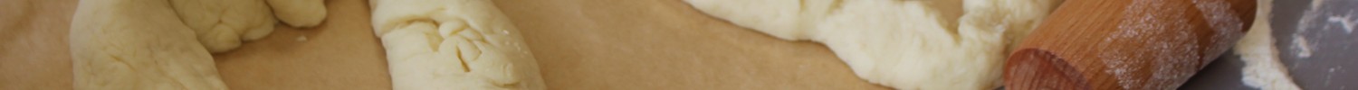 Auf dem Bild sind zwei Gebäcke und eine Teigrolle zu sehen, die im Rahmen des Bäcker-Moduls erstellt wurden.